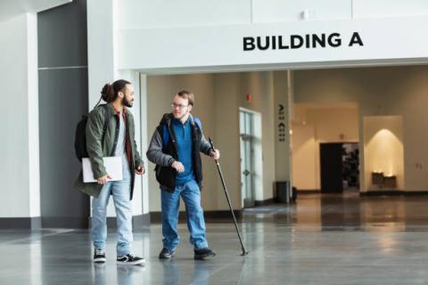 Image of an adult walking with a student with disabilities near the entrance to a building with the label "Building A".
