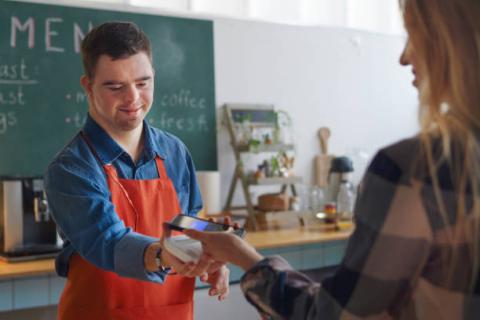 Image of employee with disabilities at a shop scanning a patron's credit card.