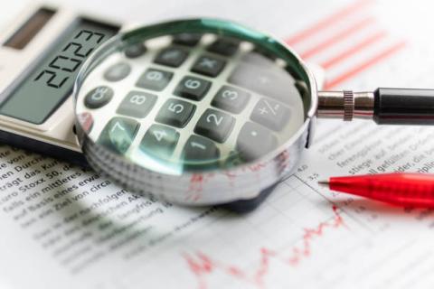 Image of a calculator with a magnifying glass over some of the number keys. The amount on the calculator screen is 2023.