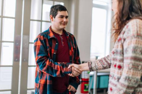 Image of foster youth shaking hands with an adult.