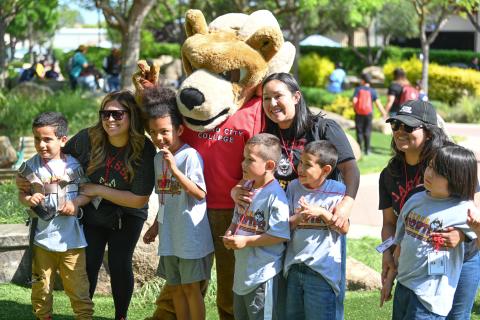 Students attending Kids' Day 2024 posing with adults and a mascot.