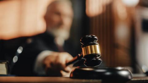 Blurred image of a judge with the gavel in the forefront.